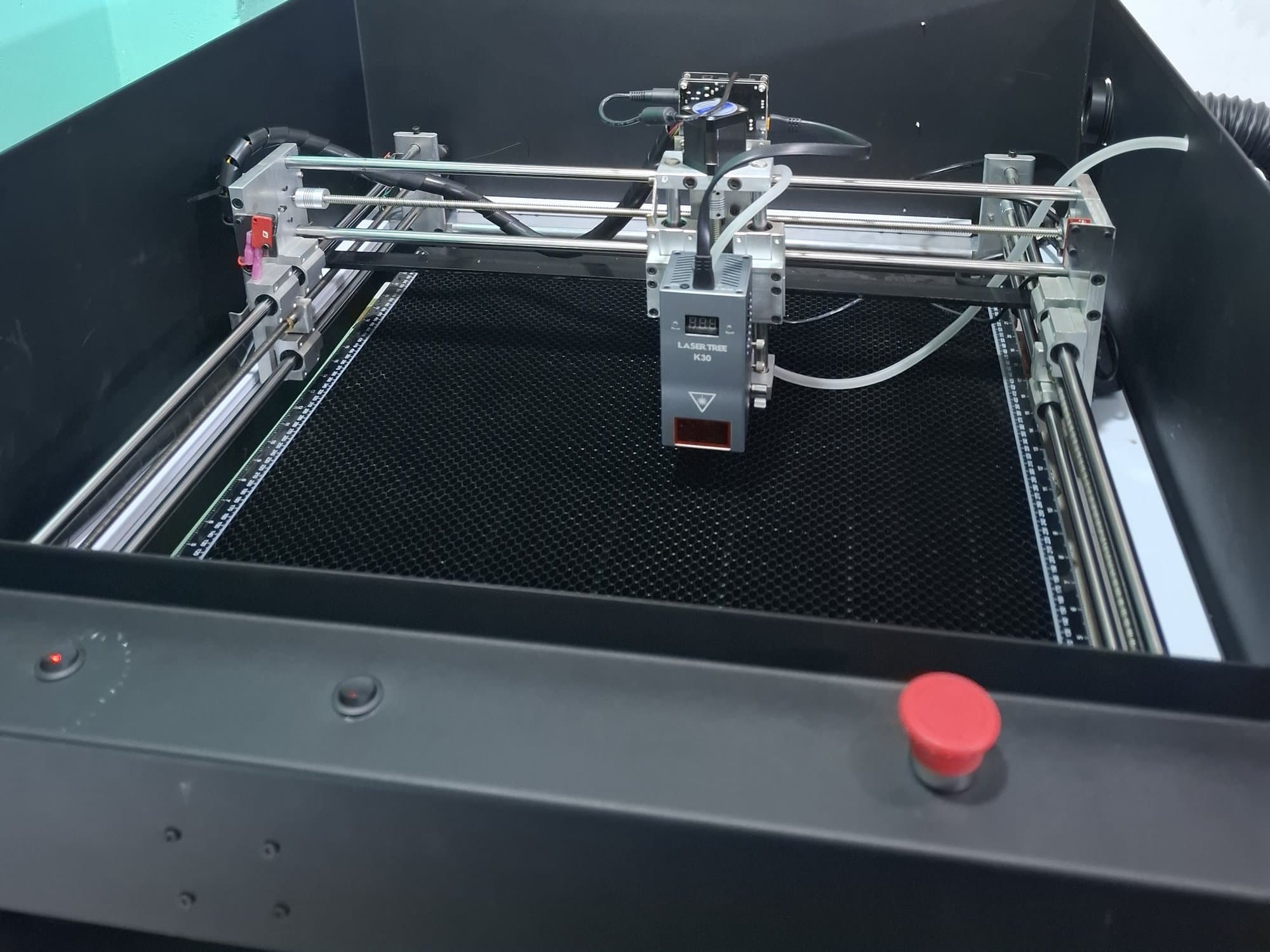 The real machine in the workshop — black cabinet, honeycomb bed, and Laser Tree K30.